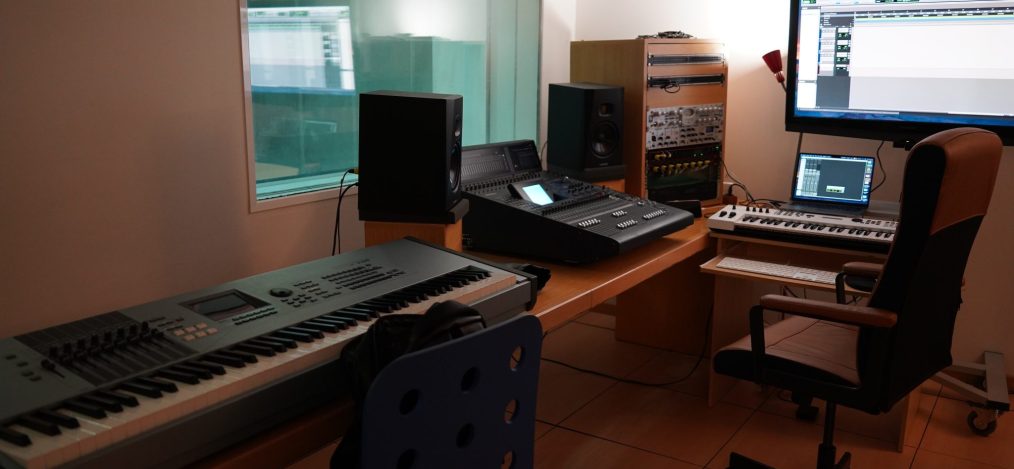Estudio de producción musical con teclados, monitores de estudio y una estación de trabajo de audio digital en pantalla