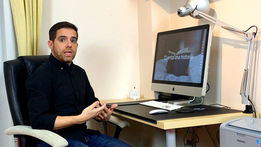 Julio en el lado izquierdo sentado en su mesa con el iMac a la derecha